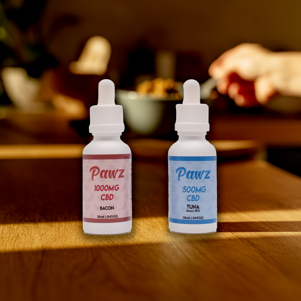 Two bottles of Pawz CBD oil on a wooden table, one bacon flavor 1000mg and one tuna flavor 500mg.