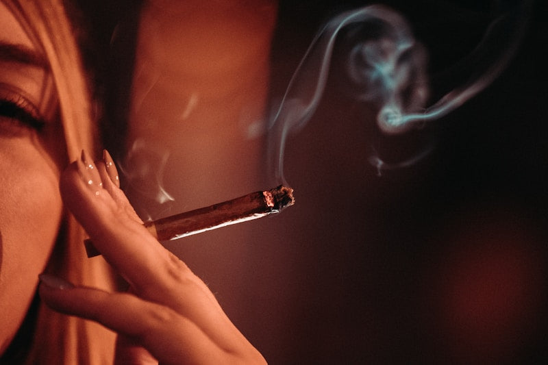 photo of a woman holding a THCA blunt with pink nails