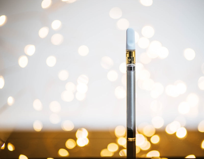 An image of a legal THC vape against a background of soft lights. Learn everything you need to know about THC vapes, including how to vape THC, in this blog from NOVA Hemp.